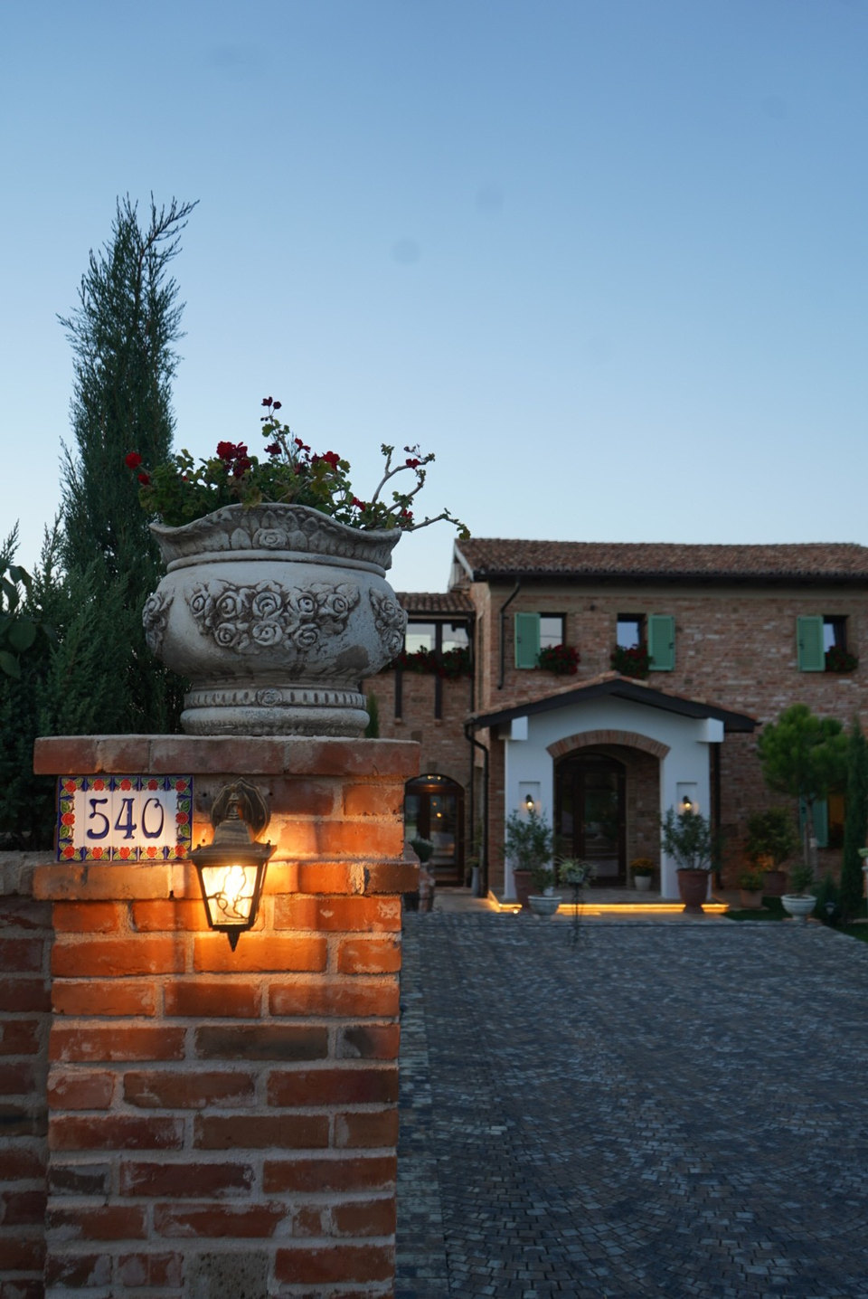 Poarta cu numărul 540, felinar aprins și vila Toscana luminată la căderea serii